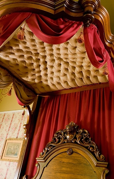 A detailed view of a four-poster bed with a tufted canopy, showcasing the intricate craftsmanship.