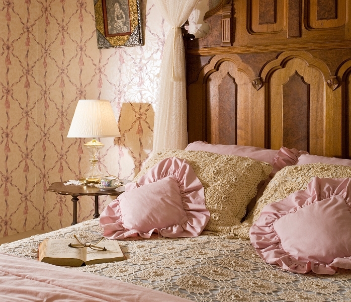 A romantic bed with a white canopy, ruffled pink pillows, and a journal open on the bed.