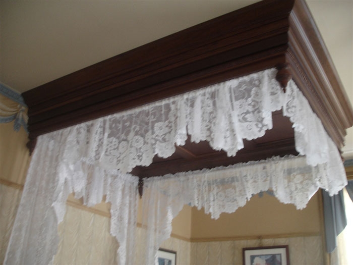 A close-up of a four-poster bed with a white lace canopy.