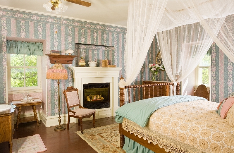 A charming bedroom with a four-poster bed, a fireplace, and a sitting area.