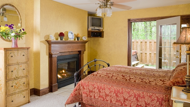 A comfortable bedroom with a fireplace, a TV, and access to a private deck for relaxing outdoors.