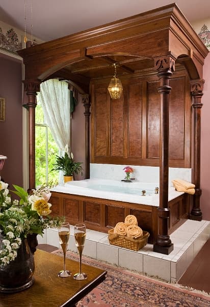 A luxurious bathroom with a large soaking tub, a fireplace, and a chandelier.