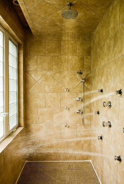 A large walk-in shower with multiple showerheads and a window.