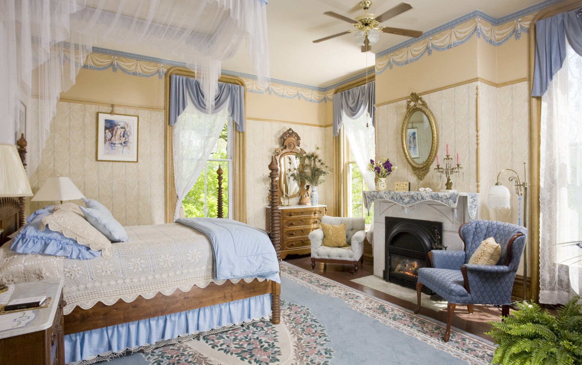 bedroom with canopy bed and chairs decorated in blue a bright light coming in from windows